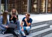 three persons sitting on the stairs talking with each other