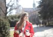 delighted female student with takeaway coffee and books in campus