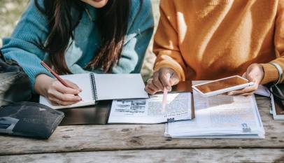 crop diverse female students fulfilling homework together in park