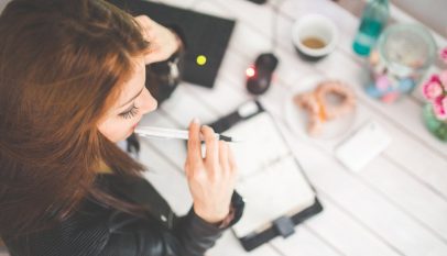 young woman thinking with pen while working studying at her desk