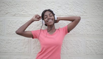 cheerful black woman with earphones dancing