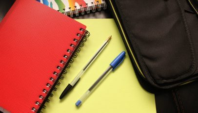 black and blue pens beside red covered notebook