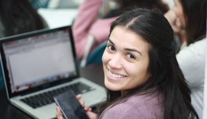 smiling woman in pink blazer using macbook pro