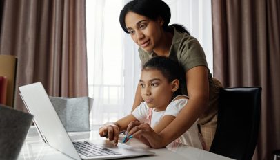 mother helping her daughter use a laptop