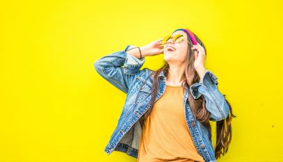 smiling woman looking upright standing against yellow wall