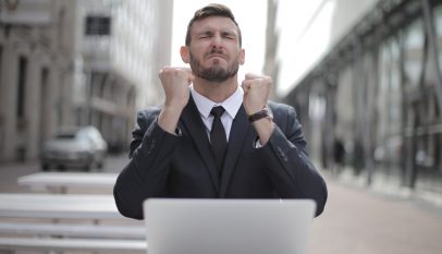 man in black suit sitting on chair beside buildings