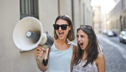 cheerful young women screaming into loudspeaker