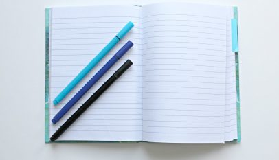 opened notebook with three assorted color pens