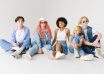 stylish multiracial models in denim outfits sitting on floor
