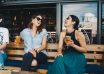 two smiling women sitting on wooden bench