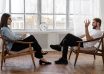 person in black pants and black shoes sitting on brown wooden chair