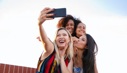 cheerful multiethnic girlfriends taking selfie on smartphone on sunny day