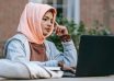 thoughtful young arab woman studying online on netbook in courtyard