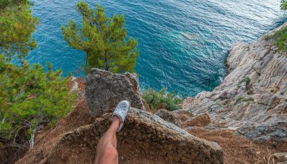 crop man standing on rock above sea