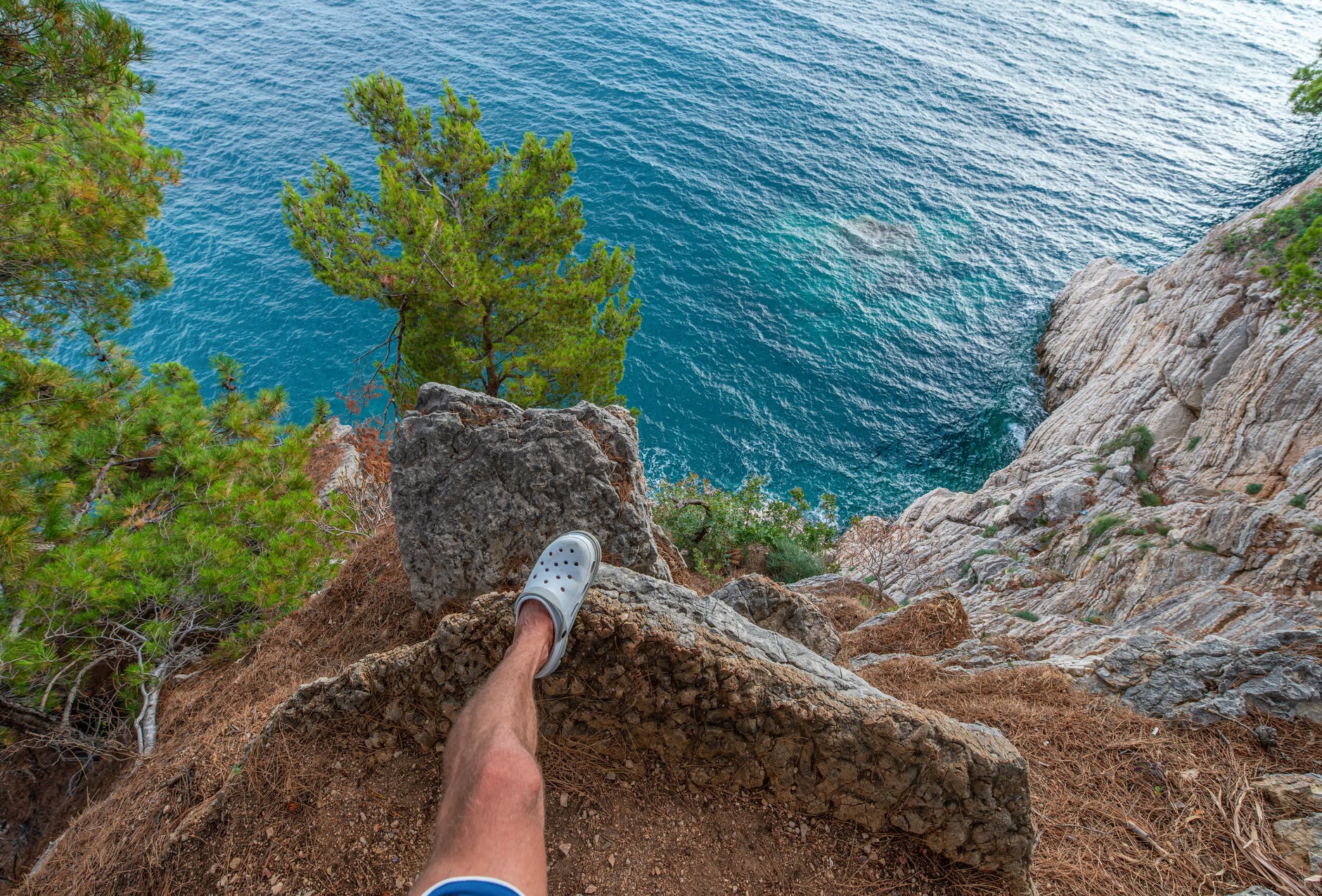 crop man standing on rock above sea