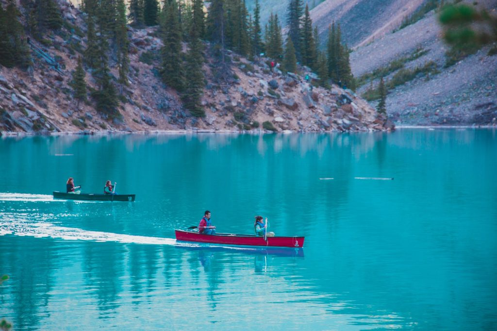 people floating in canoes on azure lake