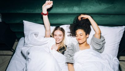 two young women lying on white bed