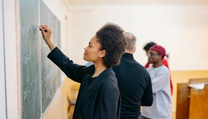 woman in black jacket writing on blackboard